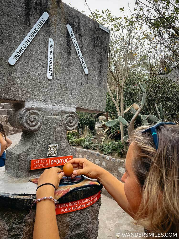 Woman balancing an egg on the 0 latitude (equator) line at the Inuit Museum, Mitad del Mundo (Middle of the World) near Quito Ecuador