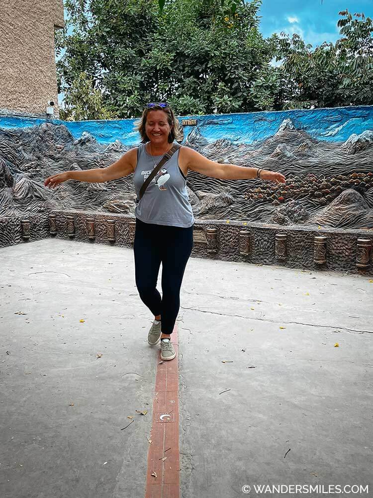 A woman trying to balance whilst walking on the 0 latitude (equator) line at the Inuit Museum, Mitad del Mundo (Middle of the World) near Quito Ecuador