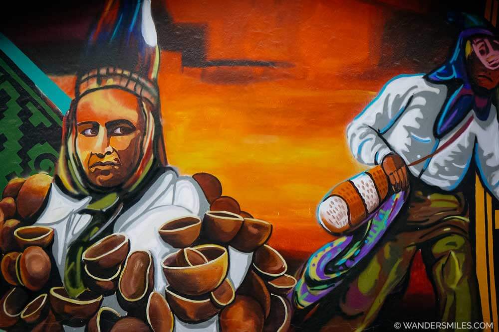 A mural depicting the Indigenous people of Ecuador with an orange sunset background. in Mural is located in Plaza de Colores in Mitad del Mundo (Middle of the World) near Quito Ecuador