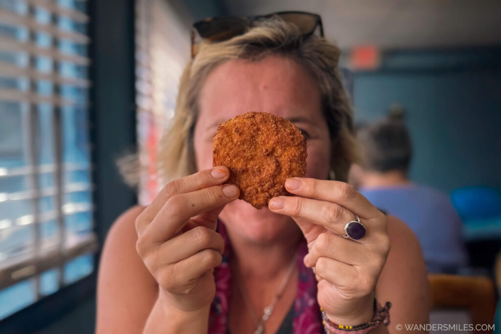 White woman with a Fried Green Tomato in front of her face. Feature image for blog about Classic Southern Dishes I ate in the Deep South USA