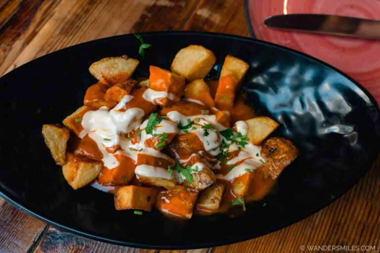 Black bowl with Patatas Bravas - Amazing Spanish Tapas with potatoes