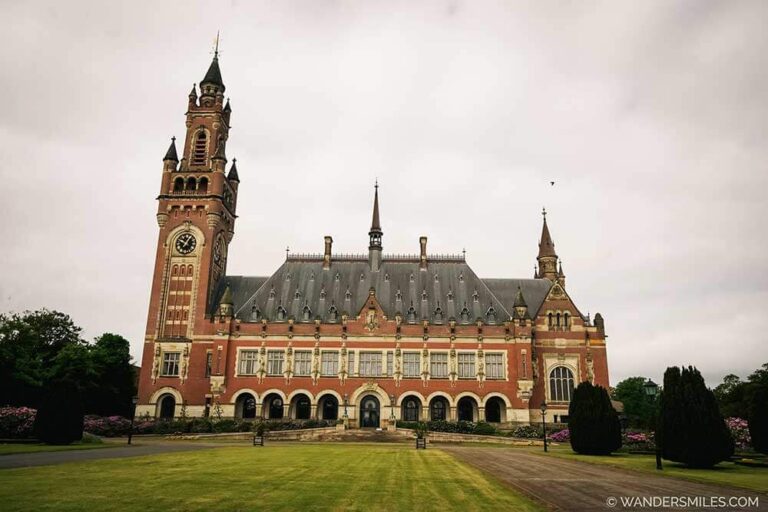 Photo of the Peace Palace, a big part of history in The Hague, Netherlands. The style of architecture is Neo-Renaissance, with green grass in the foreground.