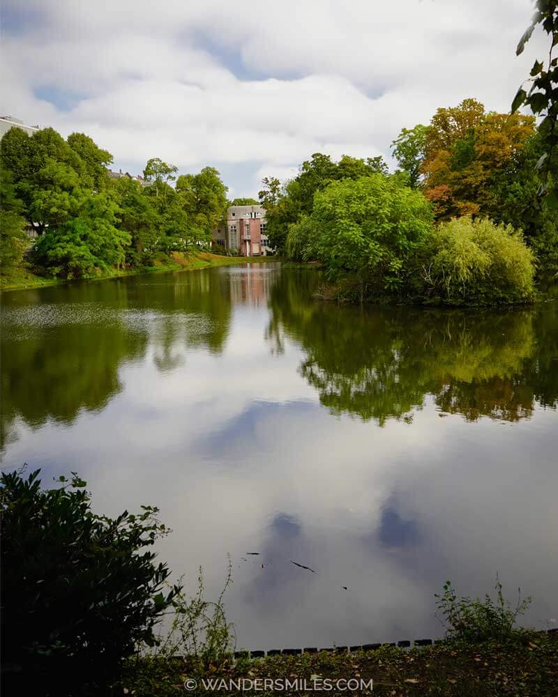 Photo in Standehaus Park, Dusseldorf, with green trees and cloud reflections on the water