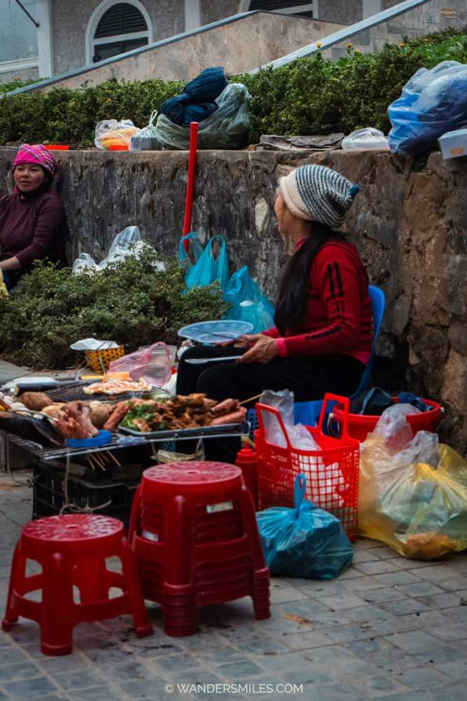 Local street food seller in Sapa, Vietnam, with a BBQ cooking meat and plastic chairs for customers