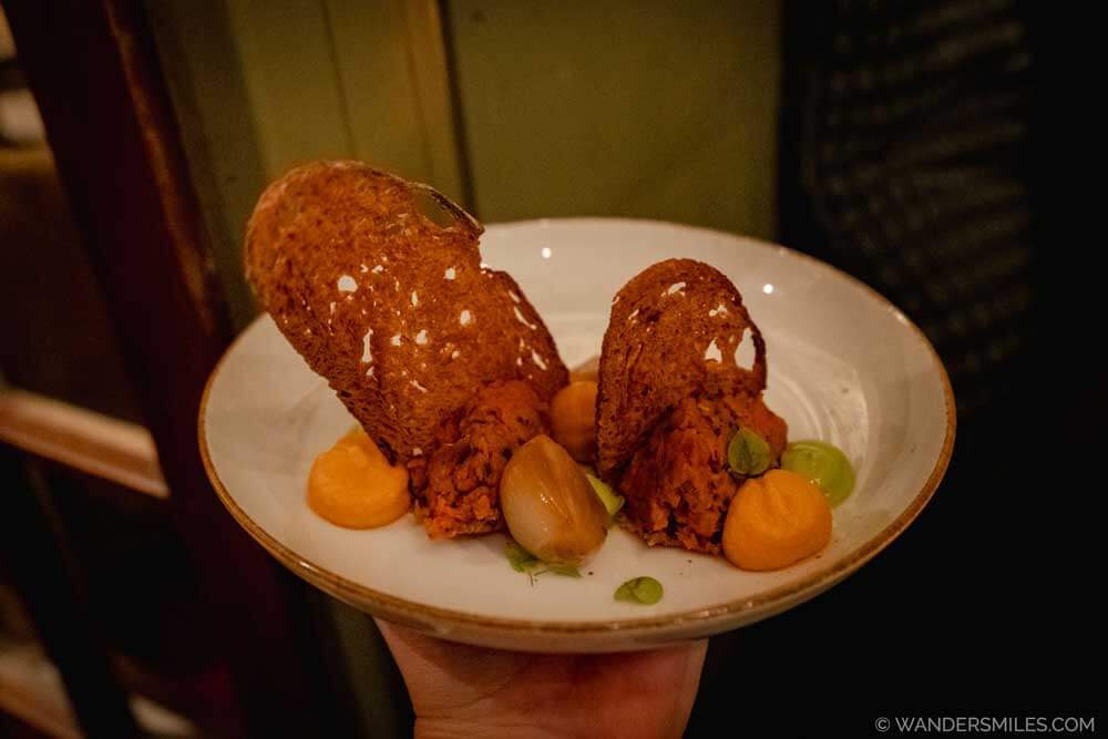 Carrot Tartare dish (includes Shallot, Lovage, Crostini, Carrot
Cream, Cornichon) in plant-based restaurant BROEI in Utrecht