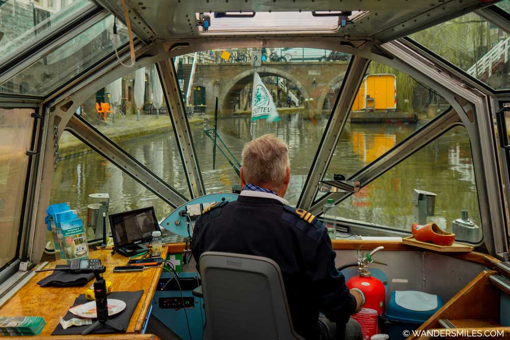 photo shows the captain with a glass-covered boat tour of the canals in Utrecht