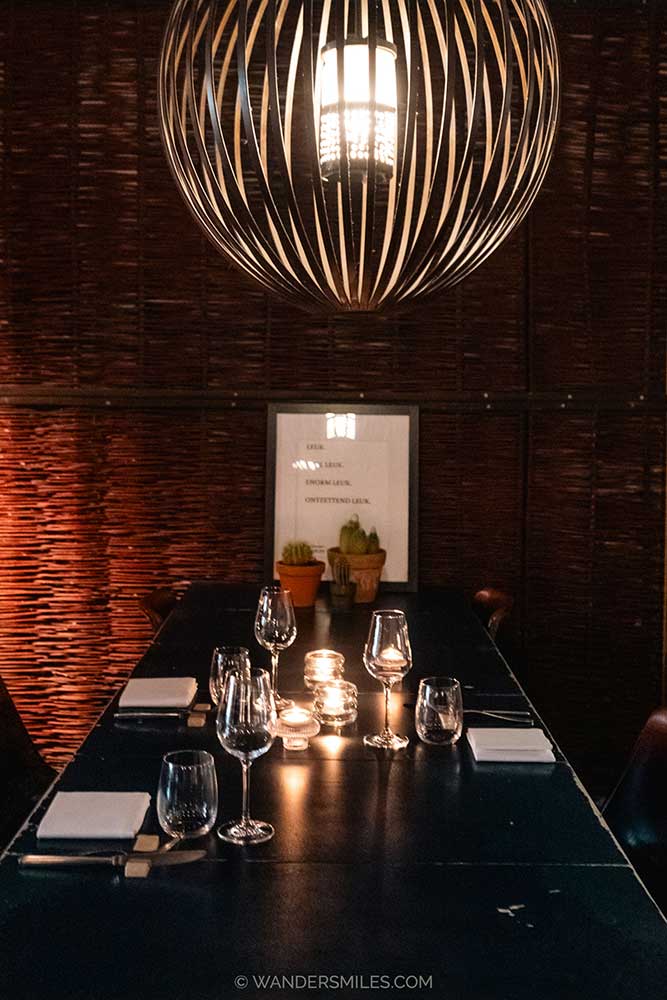 An intimate dinner setting with large round light over the table and flickering candles, at Le Jardin, Utrecht