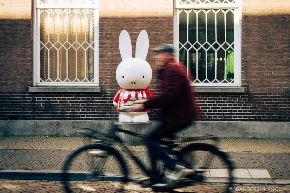 Man cycling past a Miffy statue in Utrecht outside the Miffy Museum
