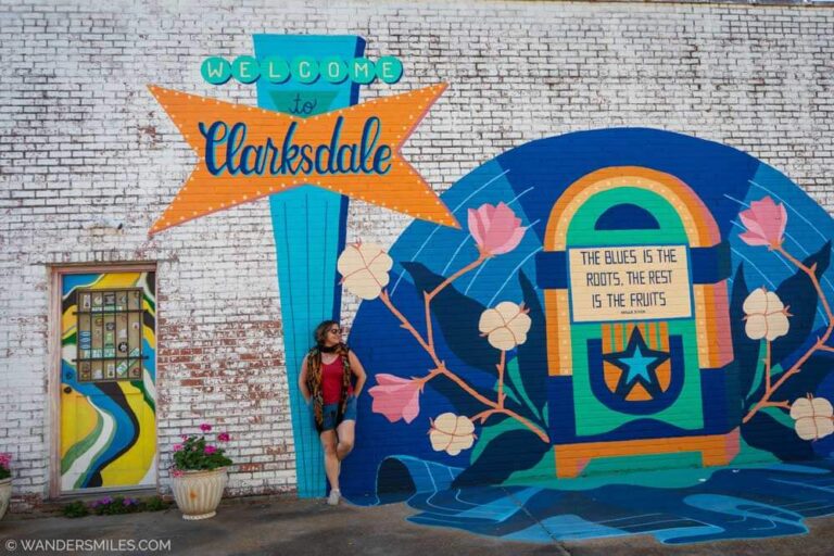 A woman in shorts leaning against a mural with "Welcome To Clarksdale". Feature photo for the blog "Cool things to do in Clarksdale"