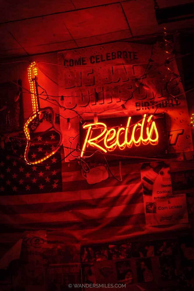 Red decor in Red's Juke Joint in Clarksdale with low neon lights with a guitar and "Redd's"