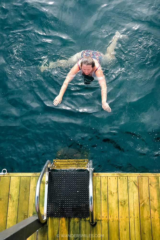 Woman doing a cold plunge off a floating sauna in Bergen harbour
