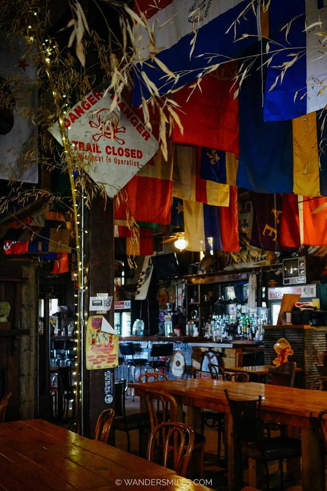 Interior of Hopson Commissary in Clarksdale MS, with flags, plants and lights hanging down from the ceiling above wooden tables
