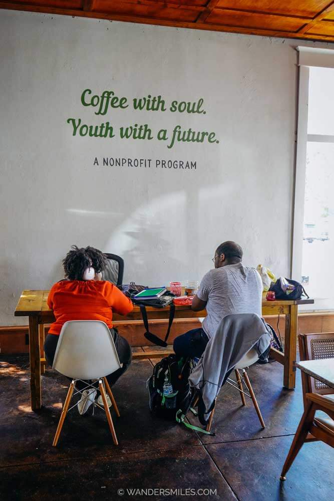 "Coffee with soup. Youth with a future" sign in Meraki Roasting Co, Clarksdale, with two you people doing crafts sat at a table