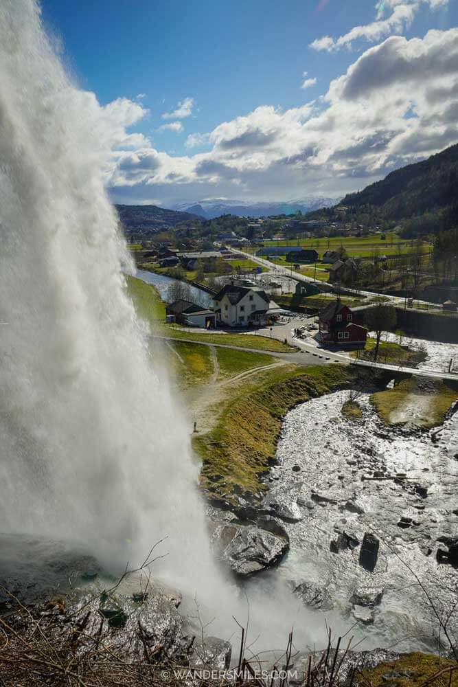 Steinsdalsfossen waterfall in Hardanger from the top with water gushing down and green landsacpe into the distance