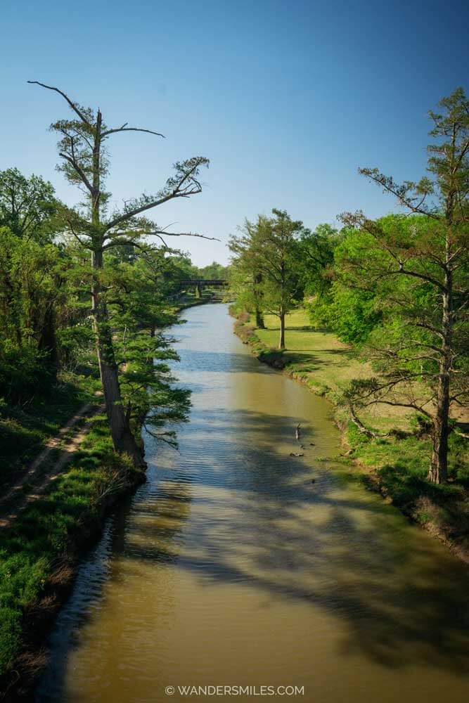 Views of Sunflower River, Clarksdale, lined with tall trees and blues skies.