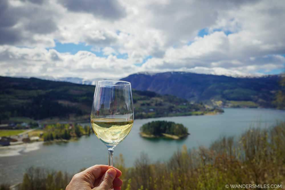 A glass of cider held up infront of fjord of Ulvik, Hardanger