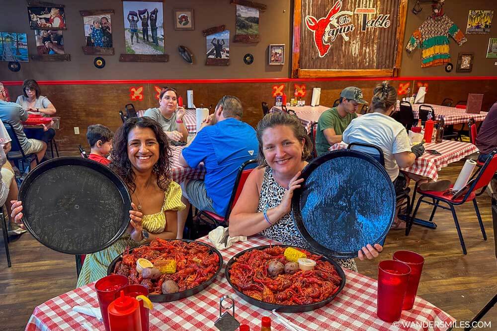 Two women with big plates of crawfish boil with sweetcorn and potatoes — one of the most famous in dishes Louisiana