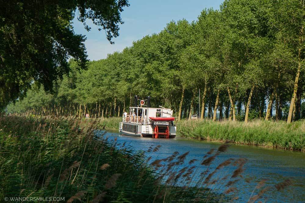The slow, white 'Lamme Goedzak' boat along the tree-lined canal between Bruges and Damme, in Flanders