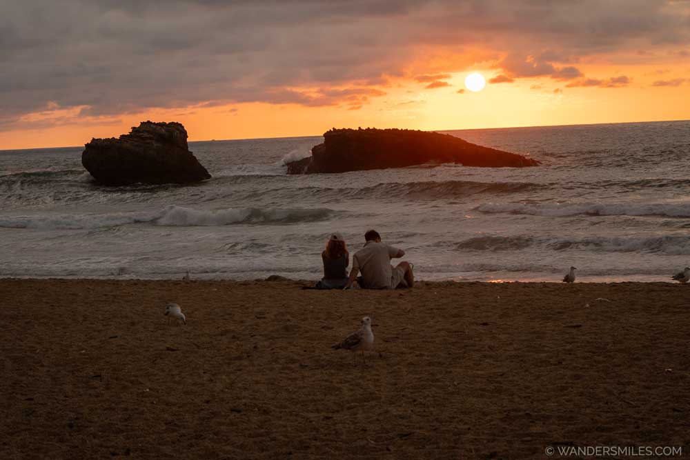 Couple sat on the beach at Biarritz at sunset