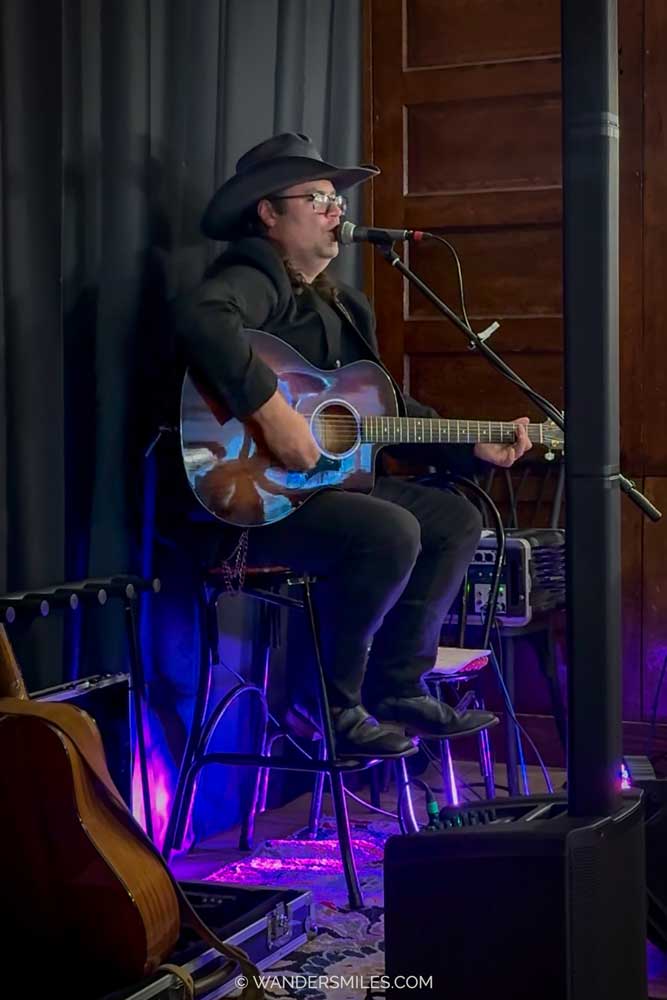 A man in a cowboy hat sat on a high stool with a guitar, singing blues in Biscuits & Blues restaurant in Natchez