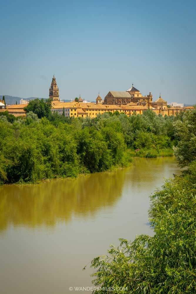 Cordoba views of Mosque-Cathedral in the distance with trees and Guadalquivir River in the foreground