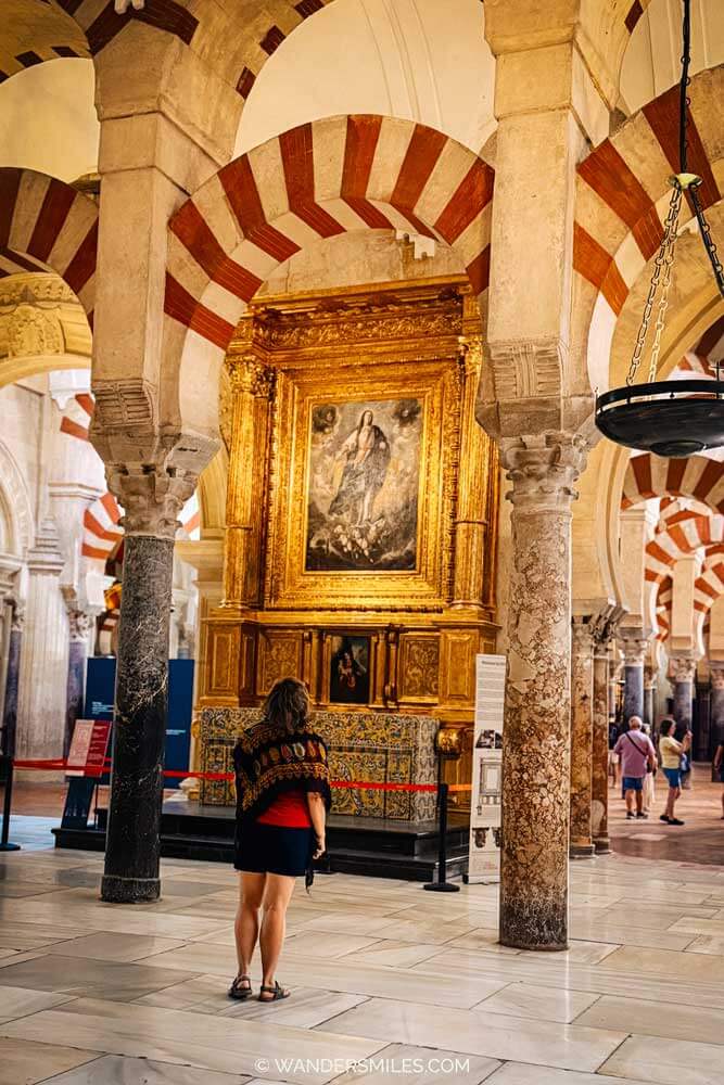 Woman in the Mosque-Cathedral with Córdoba, Spain. It is well known for its large prayer hall filled with a forest of columns and iconic red-and-white striped double arches