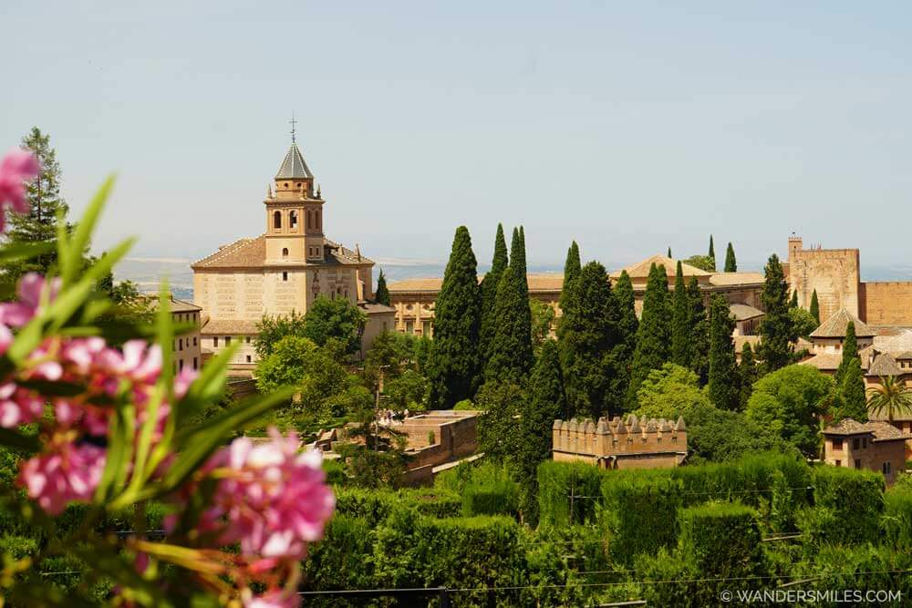 Alhambra Palace at Granada, amongst Cypress trees and pink flowers