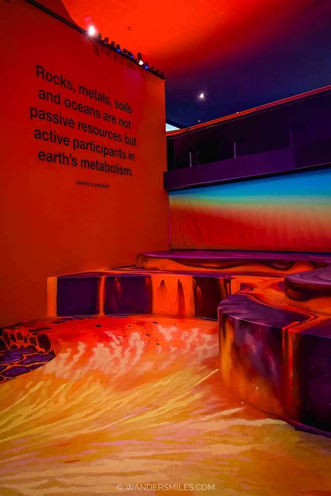 A red room at the Next Nature Museum in Eindhoven with quote "Rocks, metals, soils and oceans are not passive resources but active participants in earth's metabolism" by James Lovelock