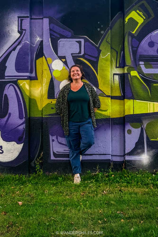 Vanessa stood against a purple and lime graffiti-style mural in "Step In The Arena" Eindhoven